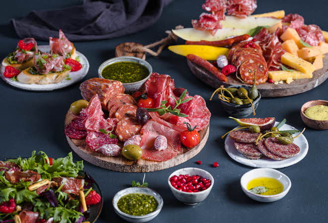 Et bord dekket med masse spekemat, ost og salat