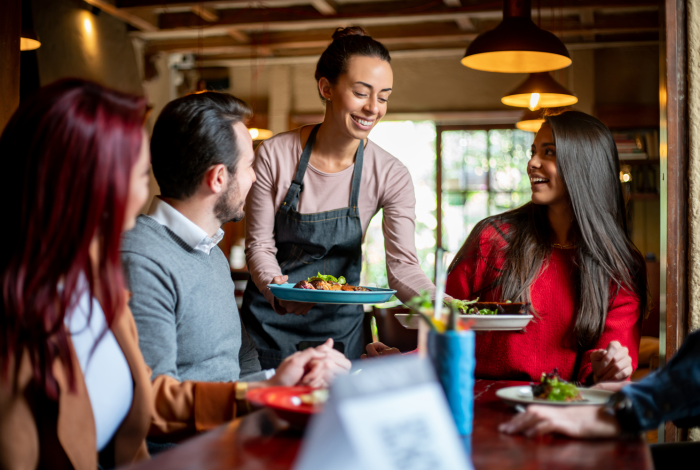 dame serverer mat til bord med tre personer