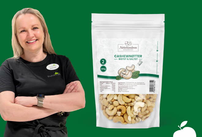 Kvinne som står med armene i kors ved siden av en pose med cashewnøtter.