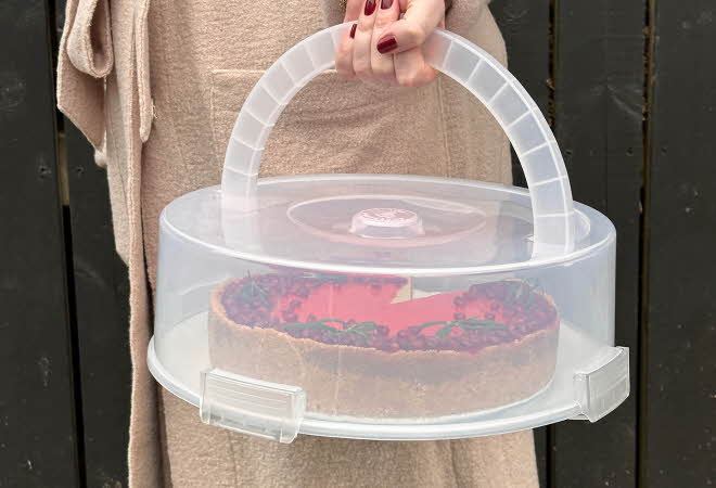 En person holder en kakeboks med en ostekake.