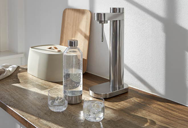 En Stelton kullsyremaskin står på en kjøkkenbenk med en flaske som er fylt med vann