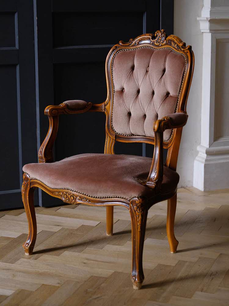 Antikk stol i barokk stil med bølgende tre og mørke, gammelrosa puter. Interiørtrend vår 2022.