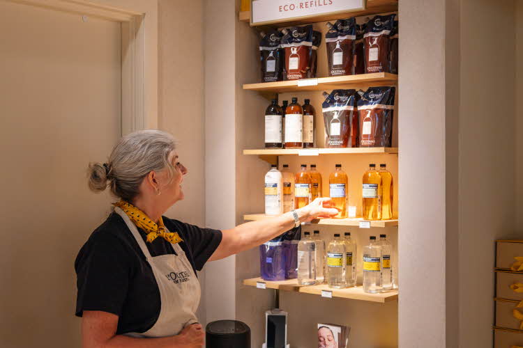 Dame fra L'Occitane viser frem produkter i hylle