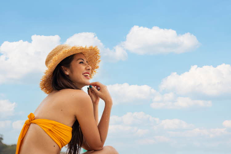 Kvinne med solhatt på stranda