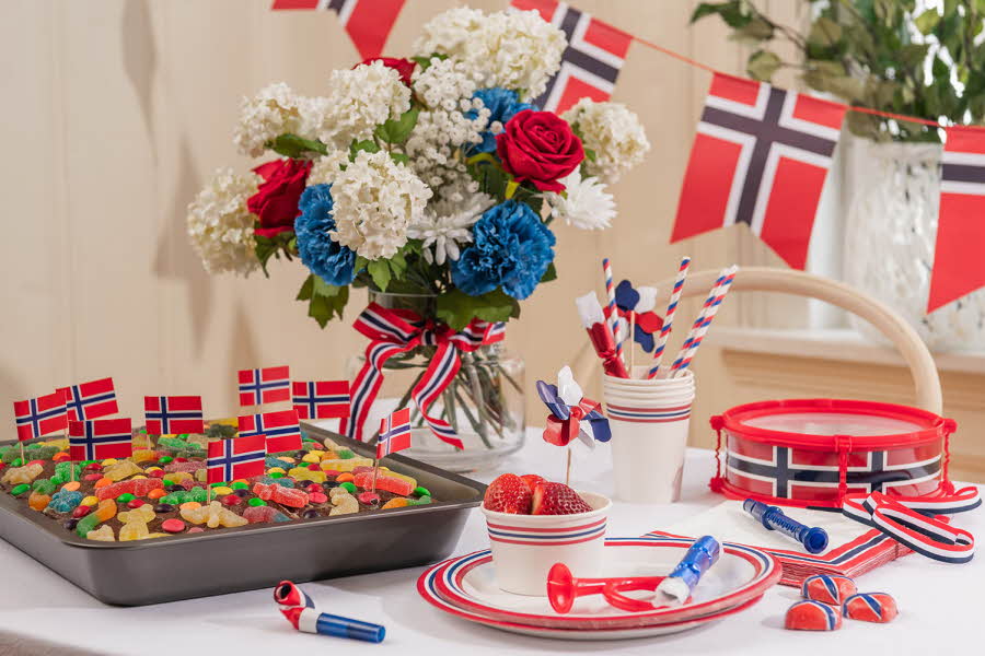 Et bord dekket til 17. mai, med masse norske flagg, en sjokoladekake og servise i rødt, hvitt og blått