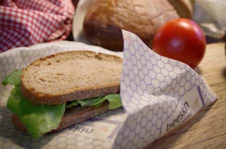 Et smurt smørbrød halvveis innpakket i bivokspapir