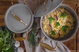 En gryte med kokt pasta, brokkoli og rødløk.