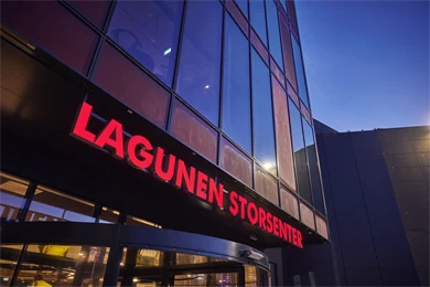 Nærbilde av fasaden til Lagunen Storsenter med skilt hvor senterets navn fremkommer med store, røde bokstaver.