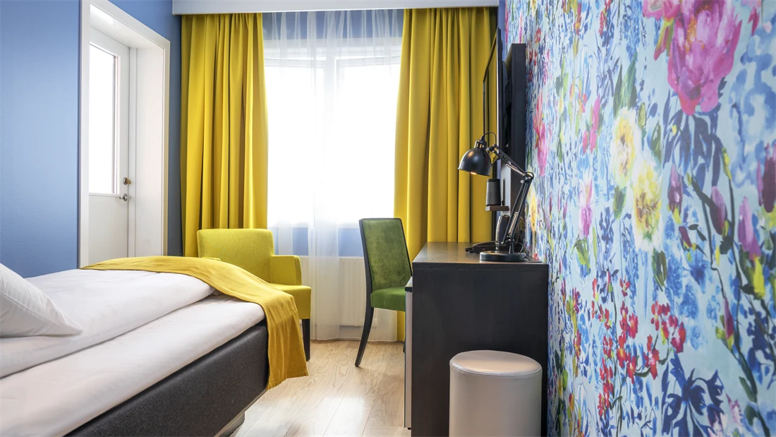 Seng, skrivebord,stol og blomstrete tapet på Thon Hotel Moldefjord