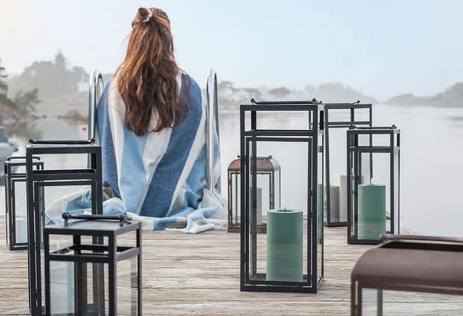 Person på brygge med blå- og hvitstripet teppe.