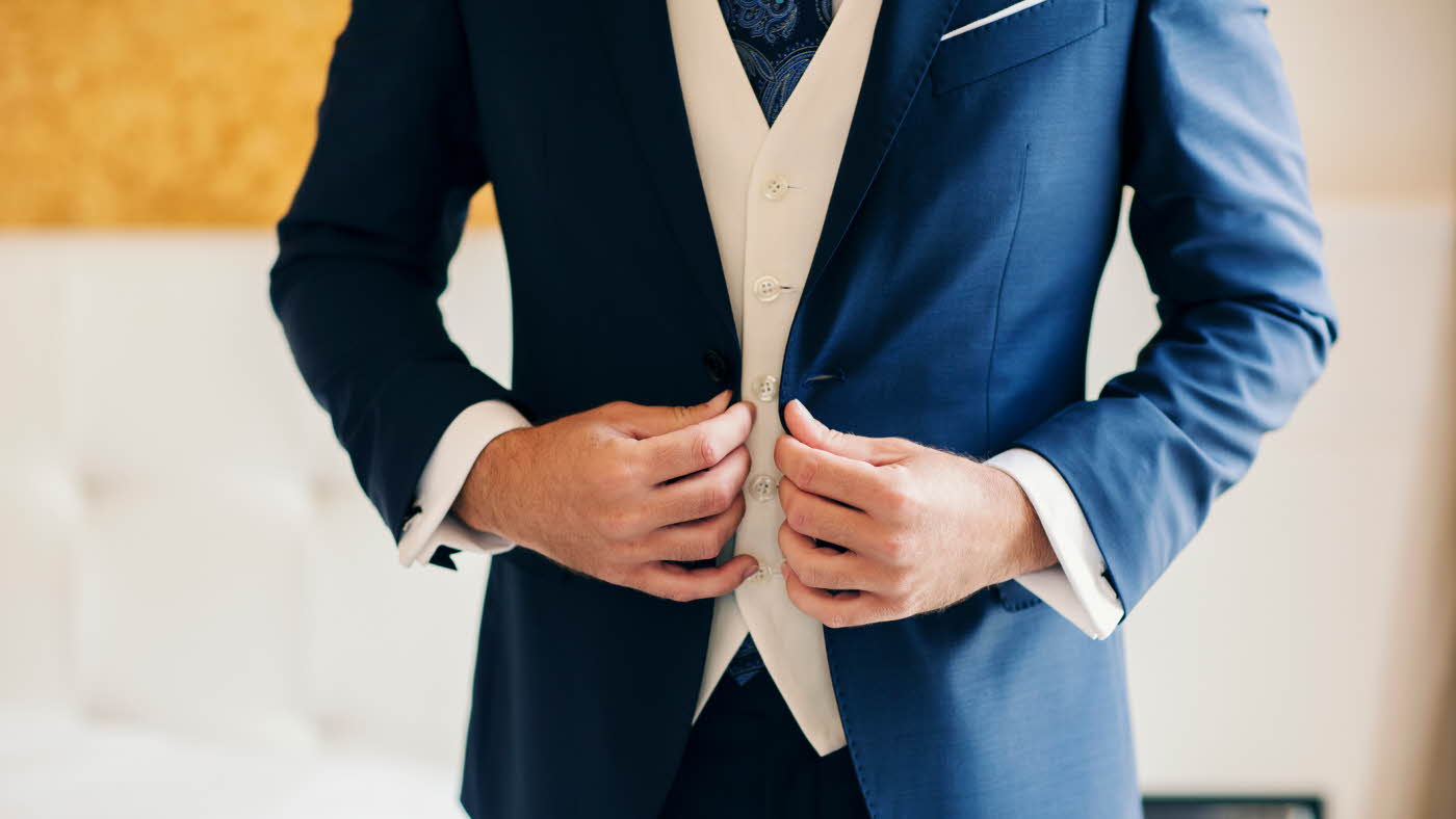 Mann i mørkeblå dress med hvit vest under