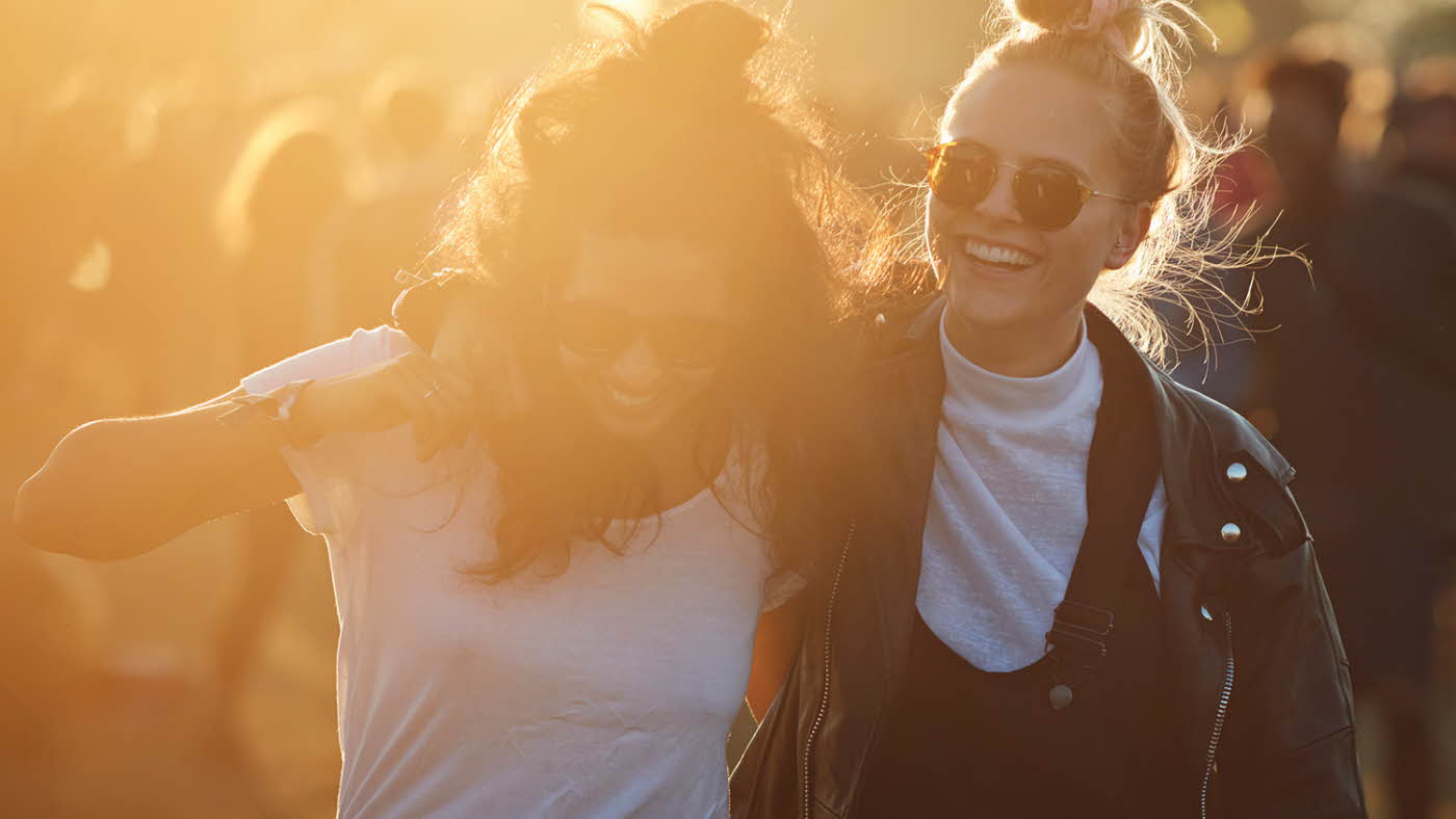 To venninner smiler og koser seg på festival