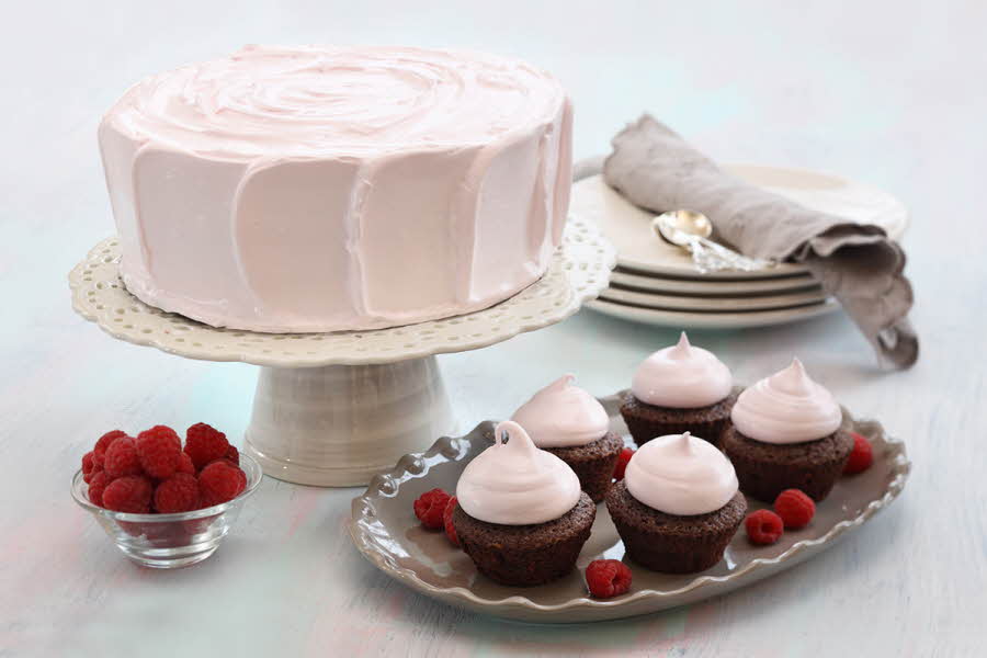Fem sjokolademuffins med rosa topping ved siden av en rosa kake