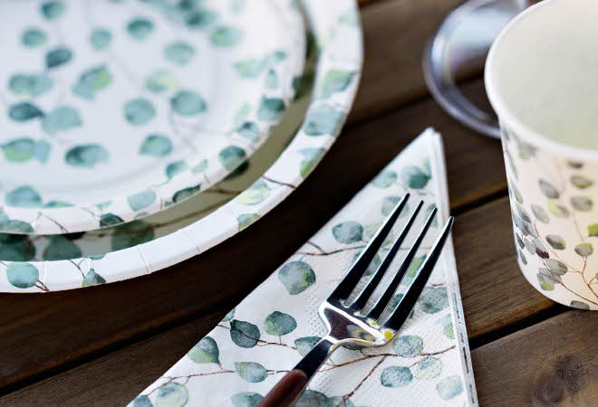 Papptallerken, serviett med gaffel og pappkrus på et bord