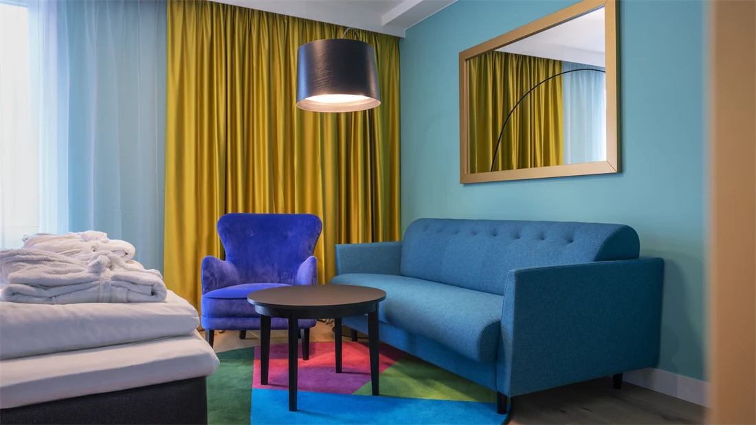 Sittegruppe med blå sofa og stol i superior HCP rom på Thon Hotel Storo