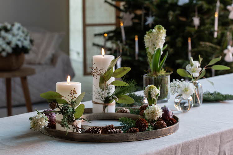Bord pyntet med kubbelys, svibler, glassvaser med hvite blomster