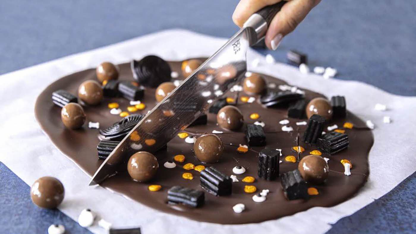 Sjokolade med Halloween-pynt og lakris på som deles med kniv
