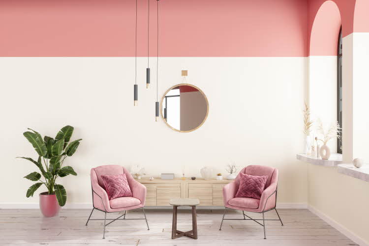 Stue med hvit og rosa vegg, speil, plante, stoler, lampe. 