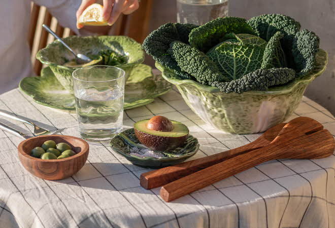 Et bord dekket med grønn salat, avocado og oliven.