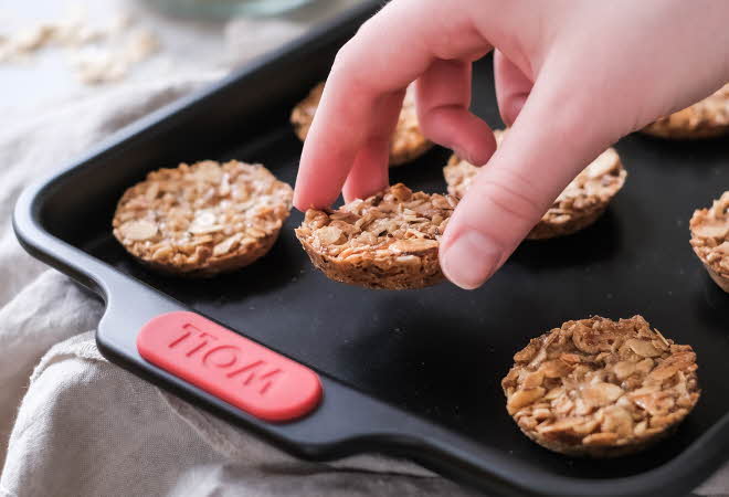 En hånd som plukker opp en kjeks fra et stekebrett.