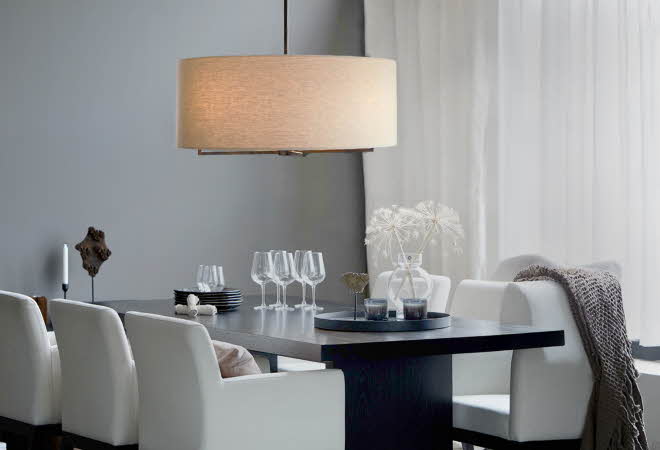 Bilde av en taklampe som henger over et spisebord med glass og tallerkener.