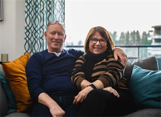 Et voksent par som sitter i en sofa