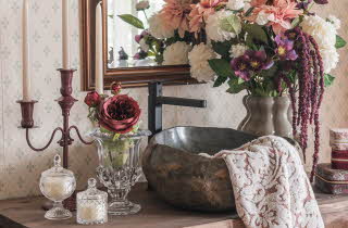 En vask på et bad med en vase med blomster og et håndkle som henger over vasken