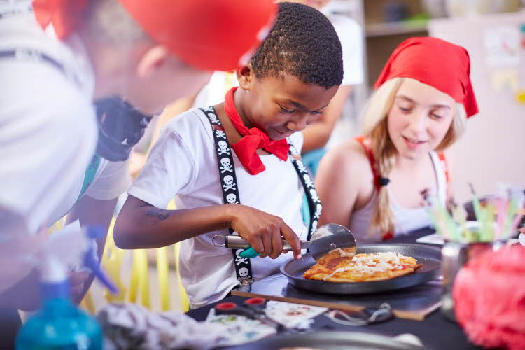 En gutt skjærer minipizza med pizzahjul
