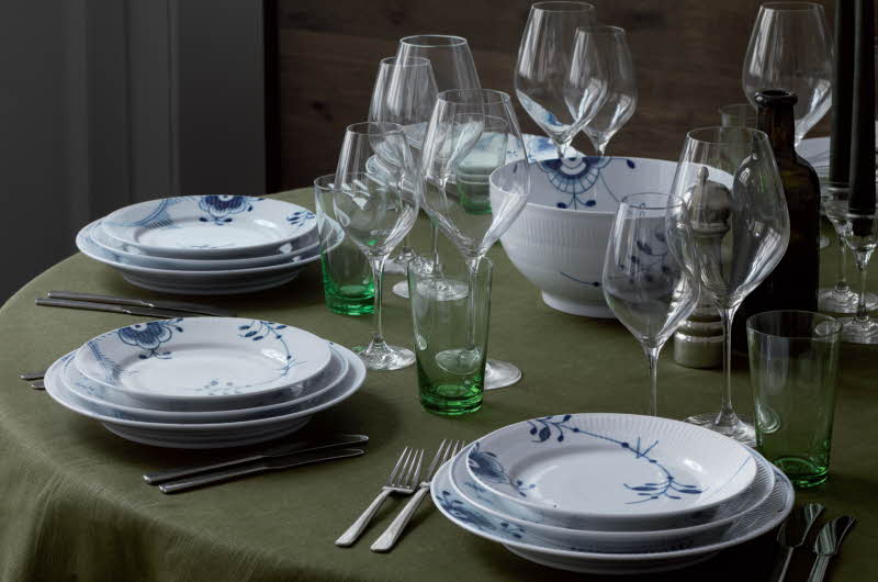 Dekket bord med grønn duk, tallerkner, bestikk og glass