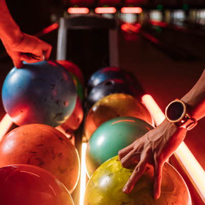 Bowlingkuler på rekke i grønn, oransje, blå og rosa