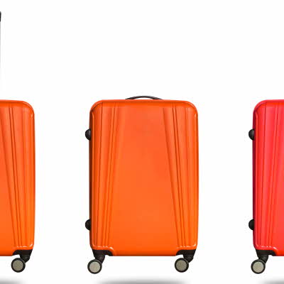 Tre oransje kofferter med hjul