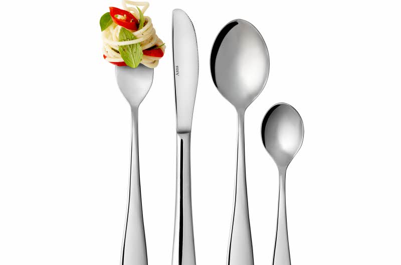 En teskje, spiseskje, kniv og gaffel fra bestikksettet Anna. Gaffelen er surret inn med spaghetti, urter og chili