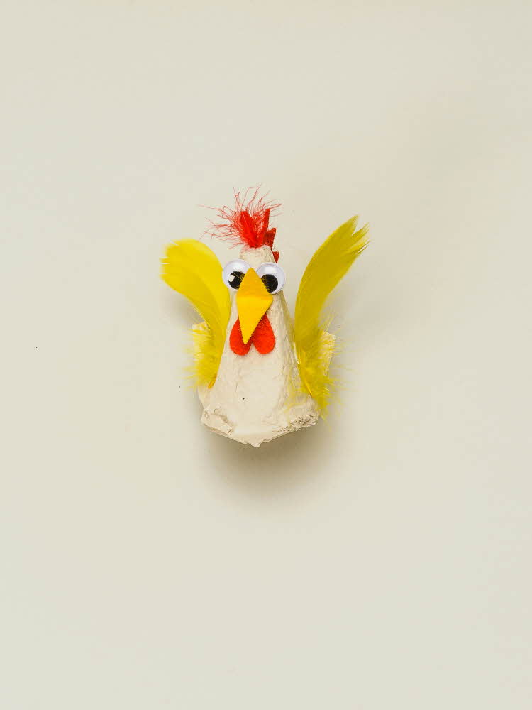 En eggekartong omgjort til en høne som mangler vinger Høne laget av eggekartong, filtbiter og fjær