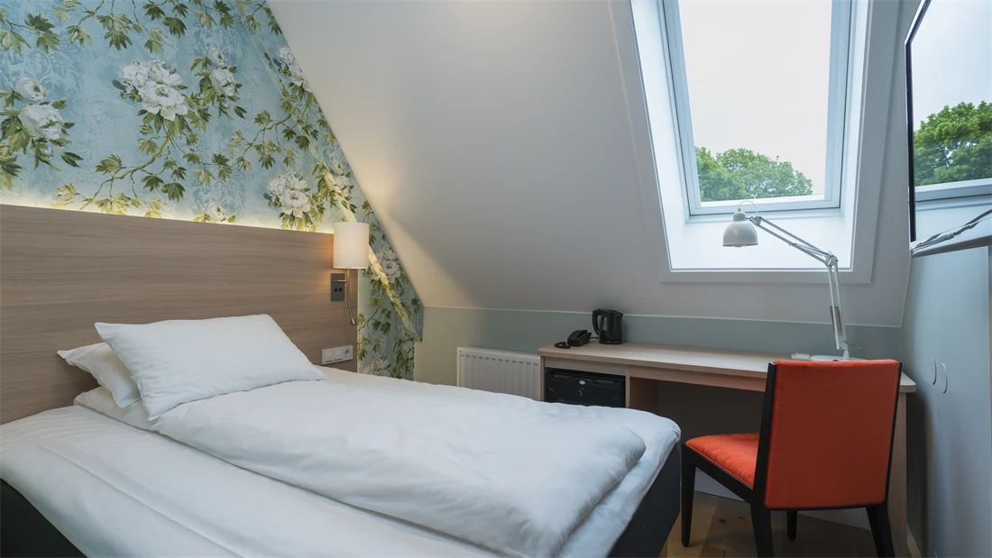 Seng og skrivebord under skråtak på standard enkeltrom på Thon Hotel Tønsberg Brygge
