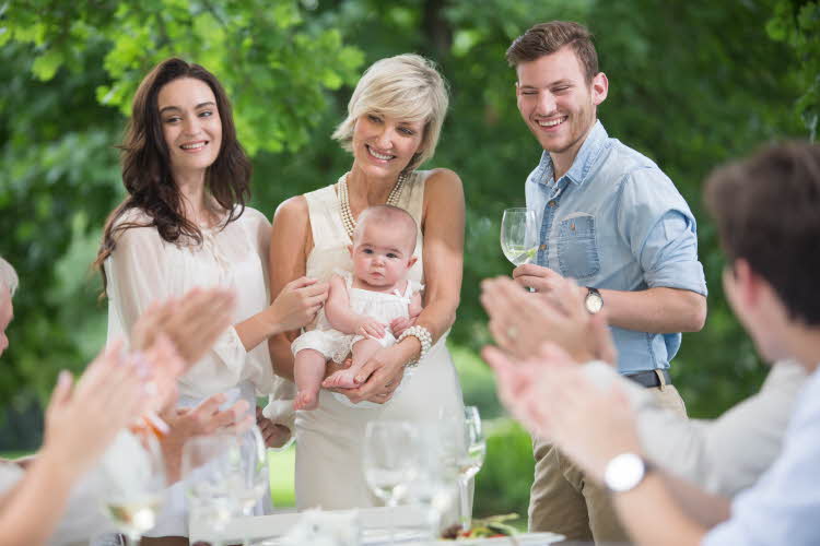 familiemiddag hvor baby blir holdt av bestemor med foreldrene og familie rundt seg