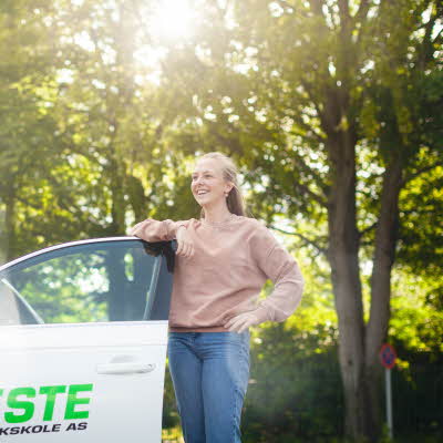 Bilde av jente på vei inn i bilen som har logo for Feste trafikkskole