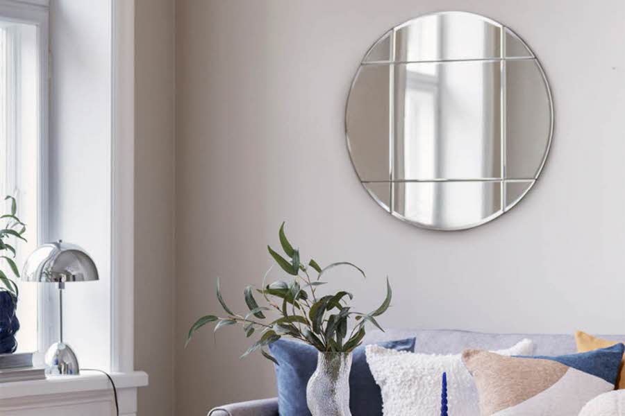 Stue med sofa, planter, lampe og rundt speil opphengt