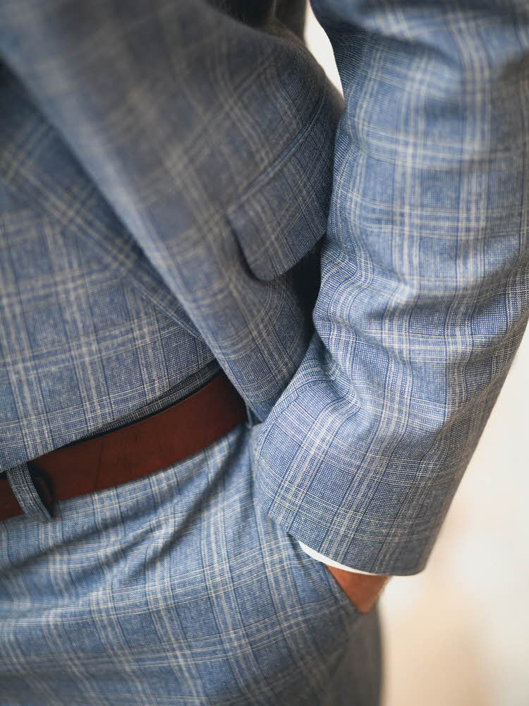 Nærbilde av mannehender i lommen på rutete dress