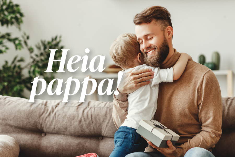 Liten gutt klemmer sin pappa som sitter i sofaen
