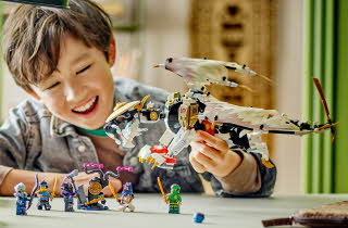 En gutt som sitter ved et bord og leker med LEGO Ninjago