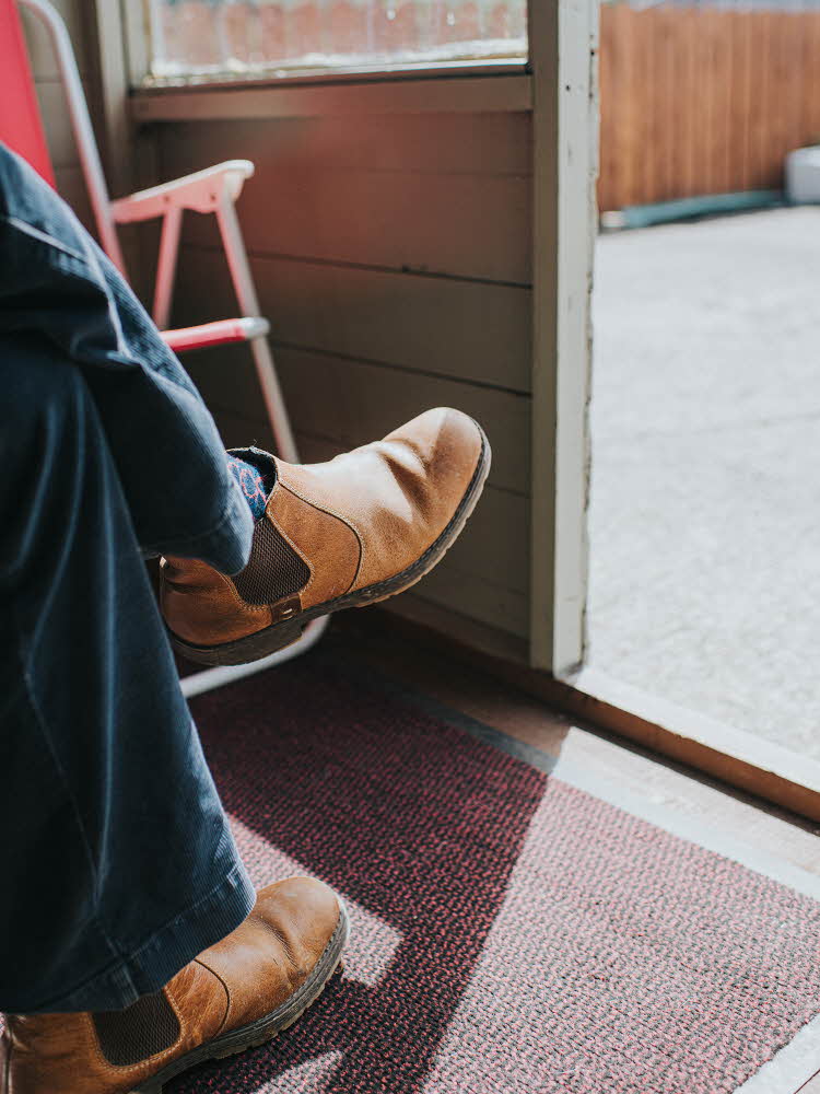 Nærbilde av ben med brune chelseaboots i døråpning