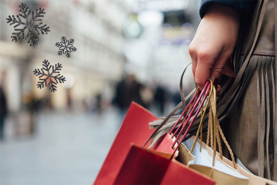 dame holder flere handleposer i shoppinggate, rød pose og beige pose. Svarte snøkrystaller