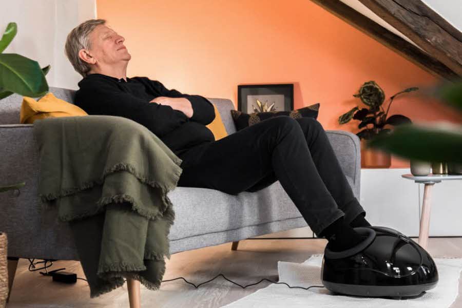 En mann som sitter i en sofa med føttene i fotmasserer