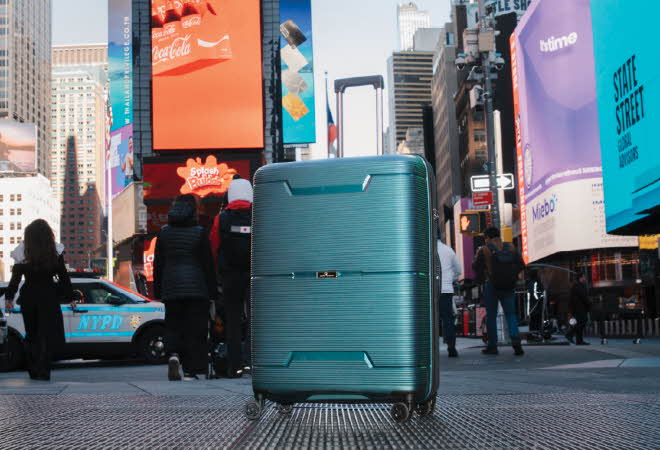 Turkis koffert med fire hjul på en gate i Times Square, New York.