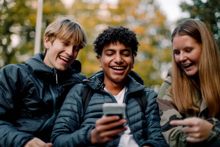 ungdommer som ser på telefon påkledd allværsjakke