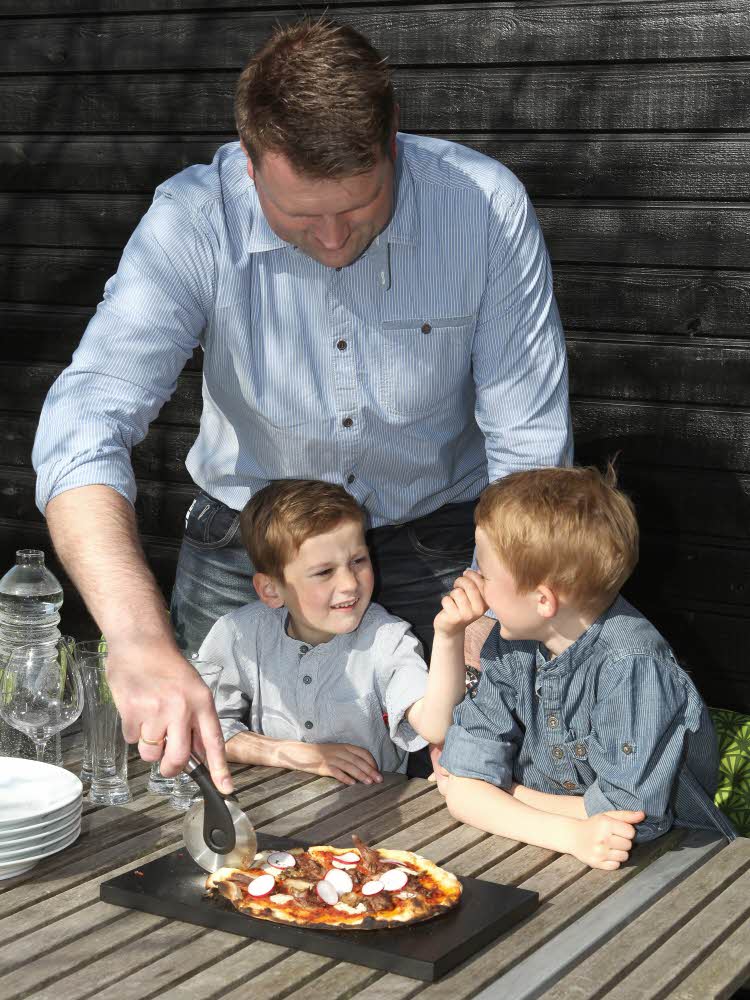 En far deler opp pizza til sine sønner