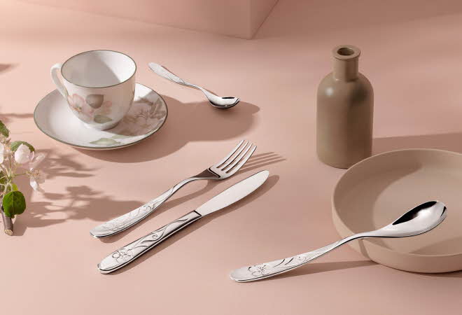 Bestikk ligger rundt en kopp og en skål og en karaffel.