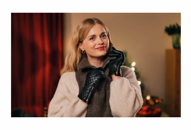 En kvinne med skinnhansker på som drar ned glidelåsen på en hals.