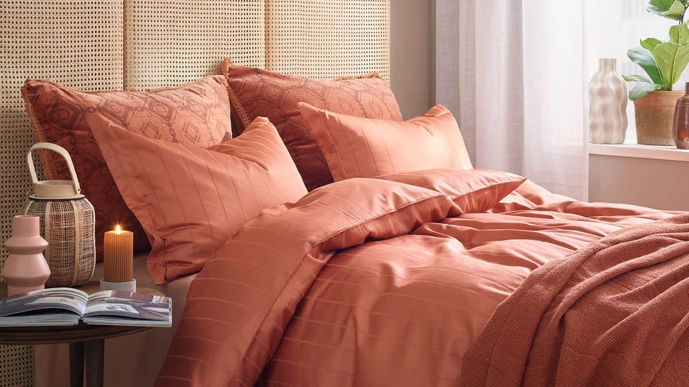 miljøbilde av seng med sengetøy i terracotta
