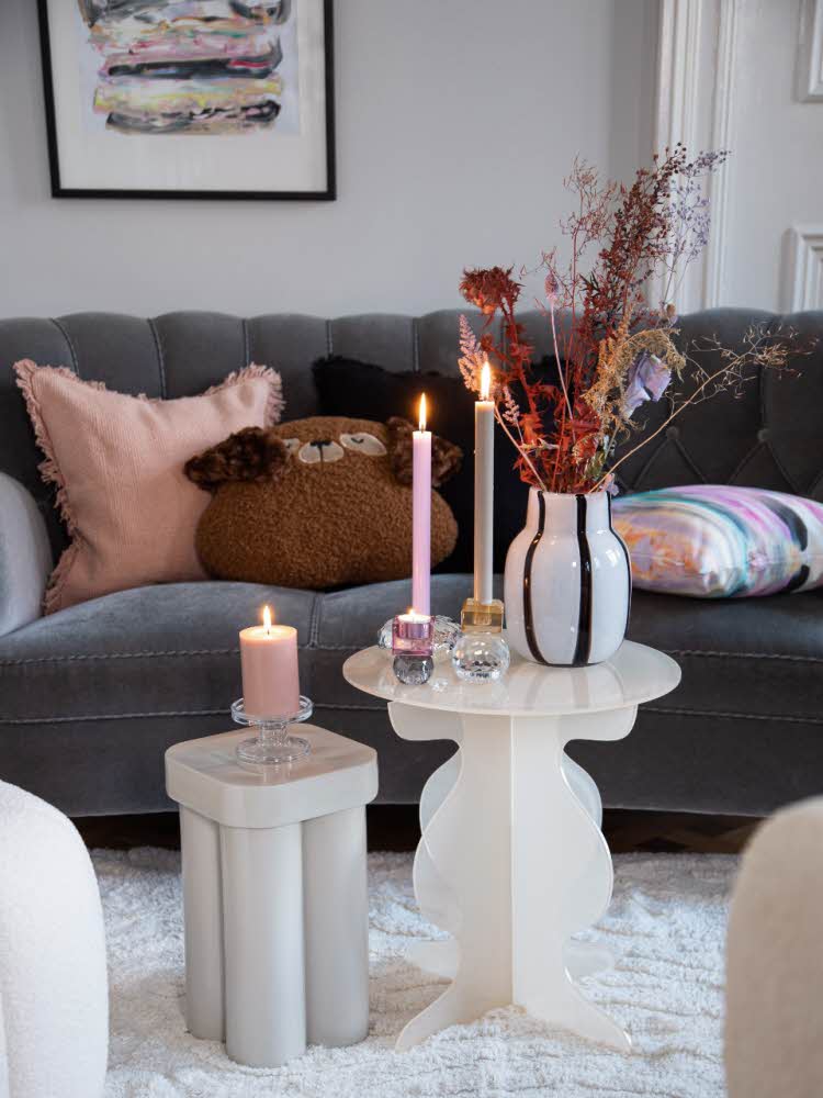 Koselig stue med puter, bord, blomster og stearinlys